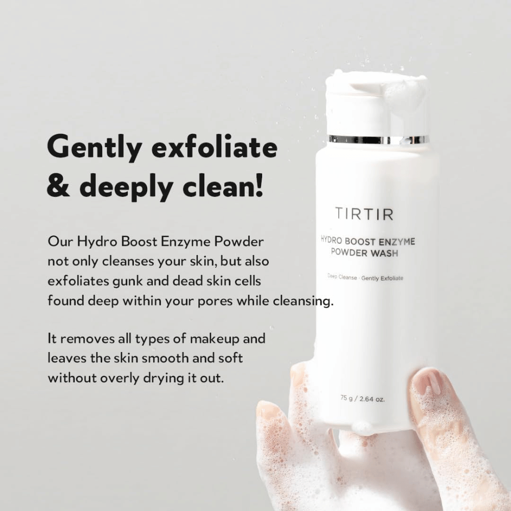 En hånd holder en flaske TIRTIR Hydro Boost Enzyme Powder Wash, et hudpleieprodukt som eksfolierer og dyprenser. Flasken er hvit med tekst, og i hånden dannes det et hvitt skum.