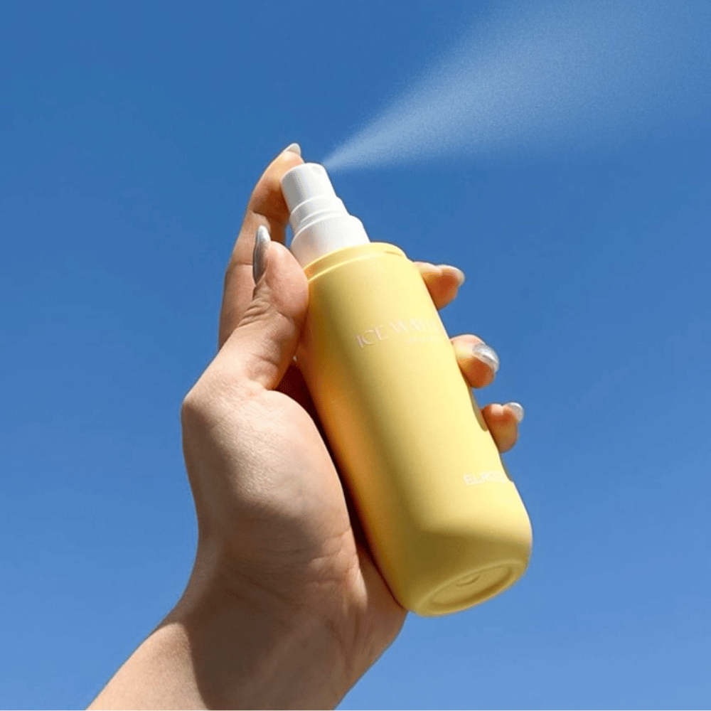 ELROEL Ice Water Sun Mist SPF 40 PA+++ solmist sprayes fra flaske mot blå himmel, lett solbeskyttelse som fukter og frisker opp huden