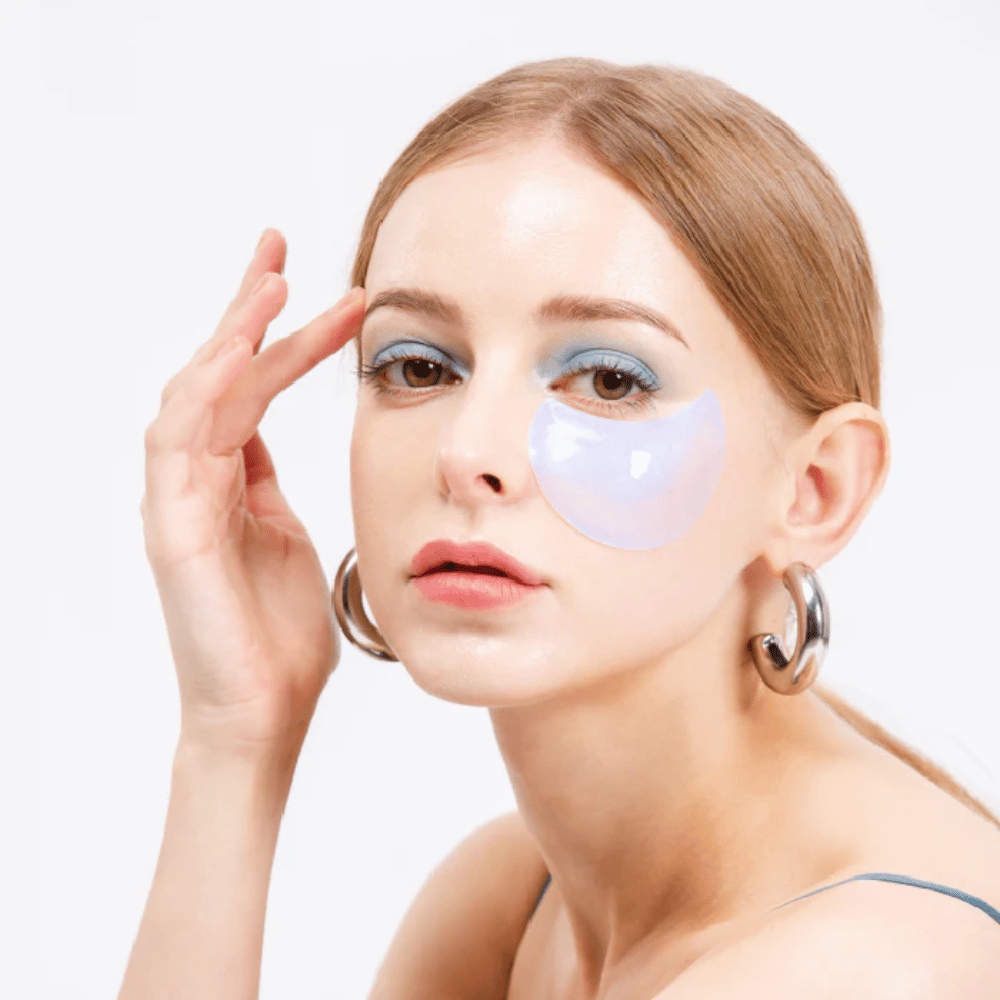 Modell bærer en blåskimrende hydrogel eye patch under øyet for en oppfriskende effekt.