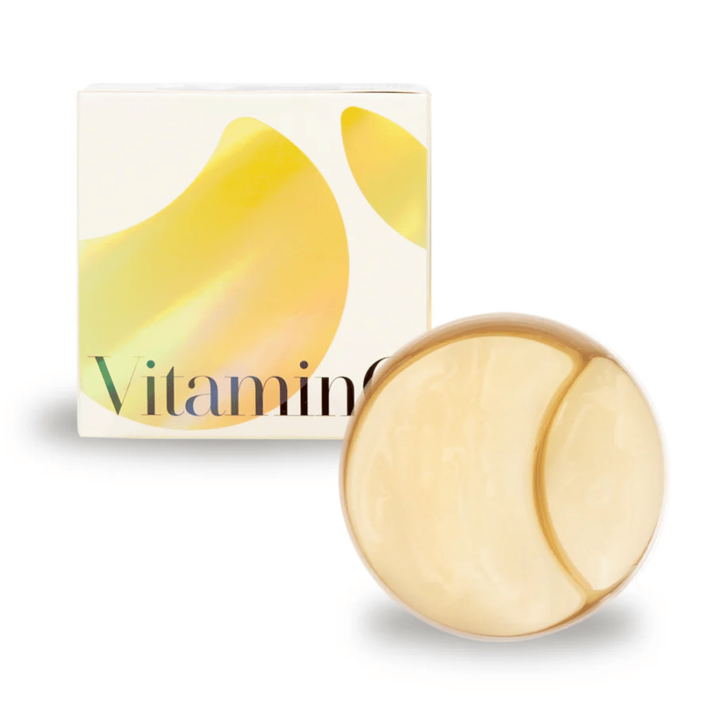 K-Secret Extra Illuminating Eye Gel Patches med vitamin C i gullskimrende hydrogel, boks og pakke i bakgrunnen.