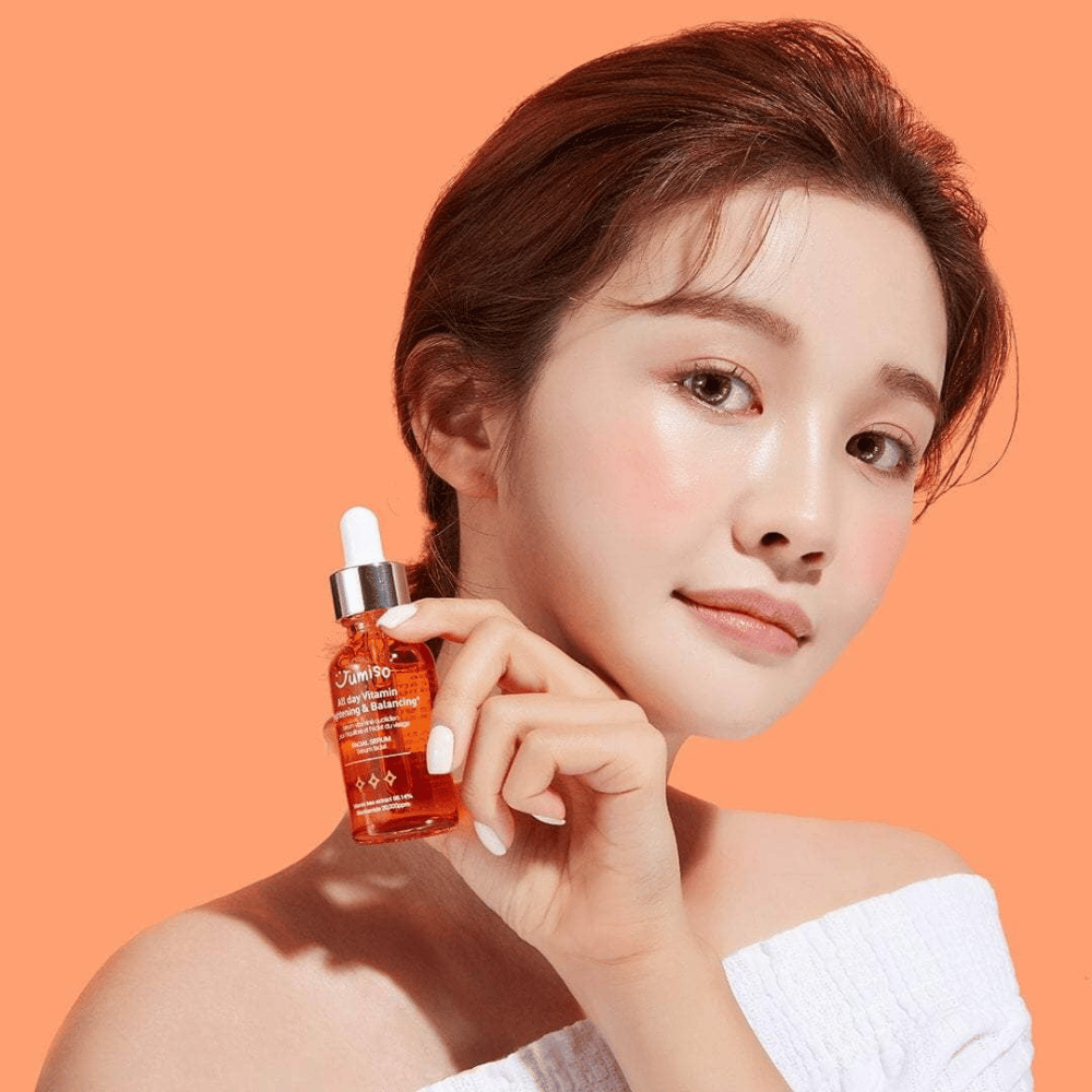 En kvinne som holder i en flaske JUMISO All Day Vitamin Brightening & Balancing Facial Serum 30ml.