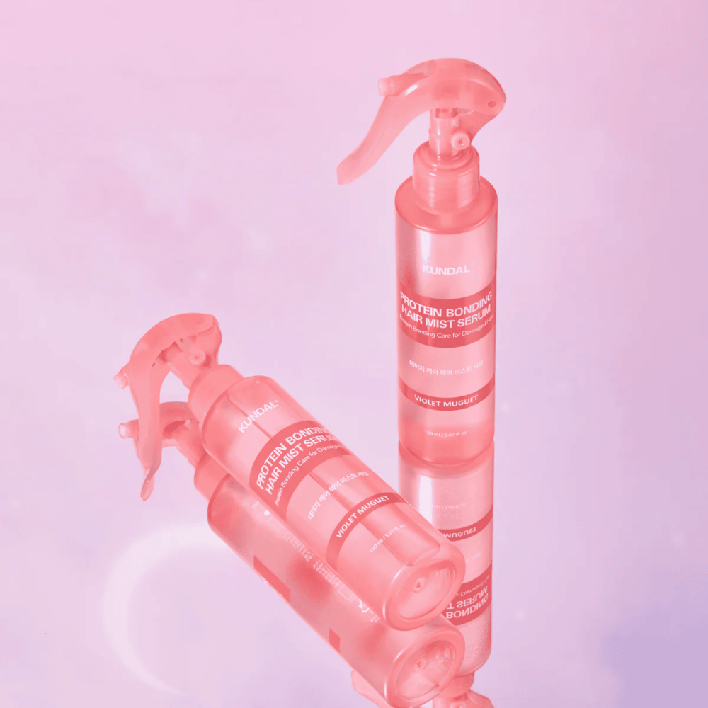 KUNDAL Protein Bonding Hair Mist Serum Violet Muguet i rosa sprayflasker, stående og liggende mot en lys rosa bakgrunn med refleksjon.