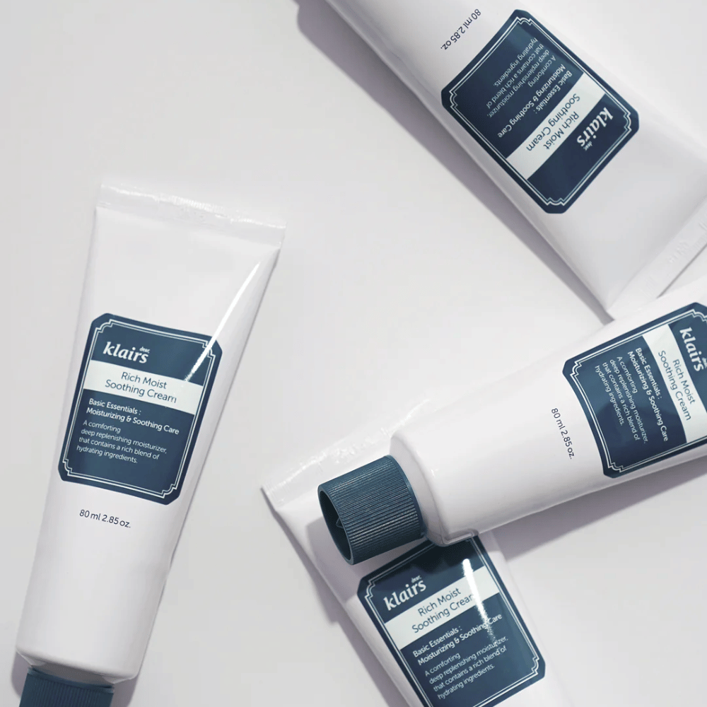 Flere tuber av Klairs Rich Moist Soothing Cream strategisk plassert på en lys overflate, med skygger som skaper dybde.