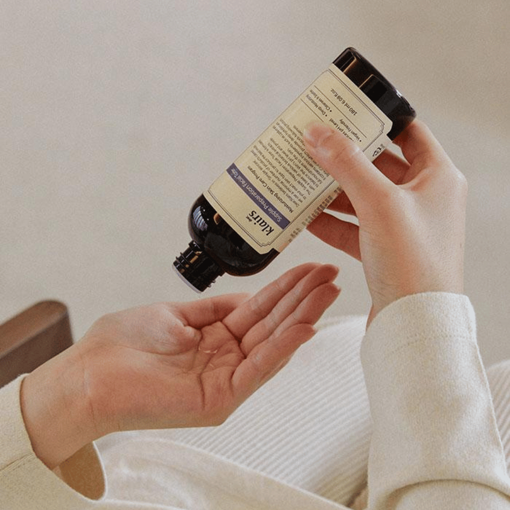En person holder en flaske av Klairs Supple Preparation Facial Toner opp og ned over hånden sin, klar til å dosere produktet.
