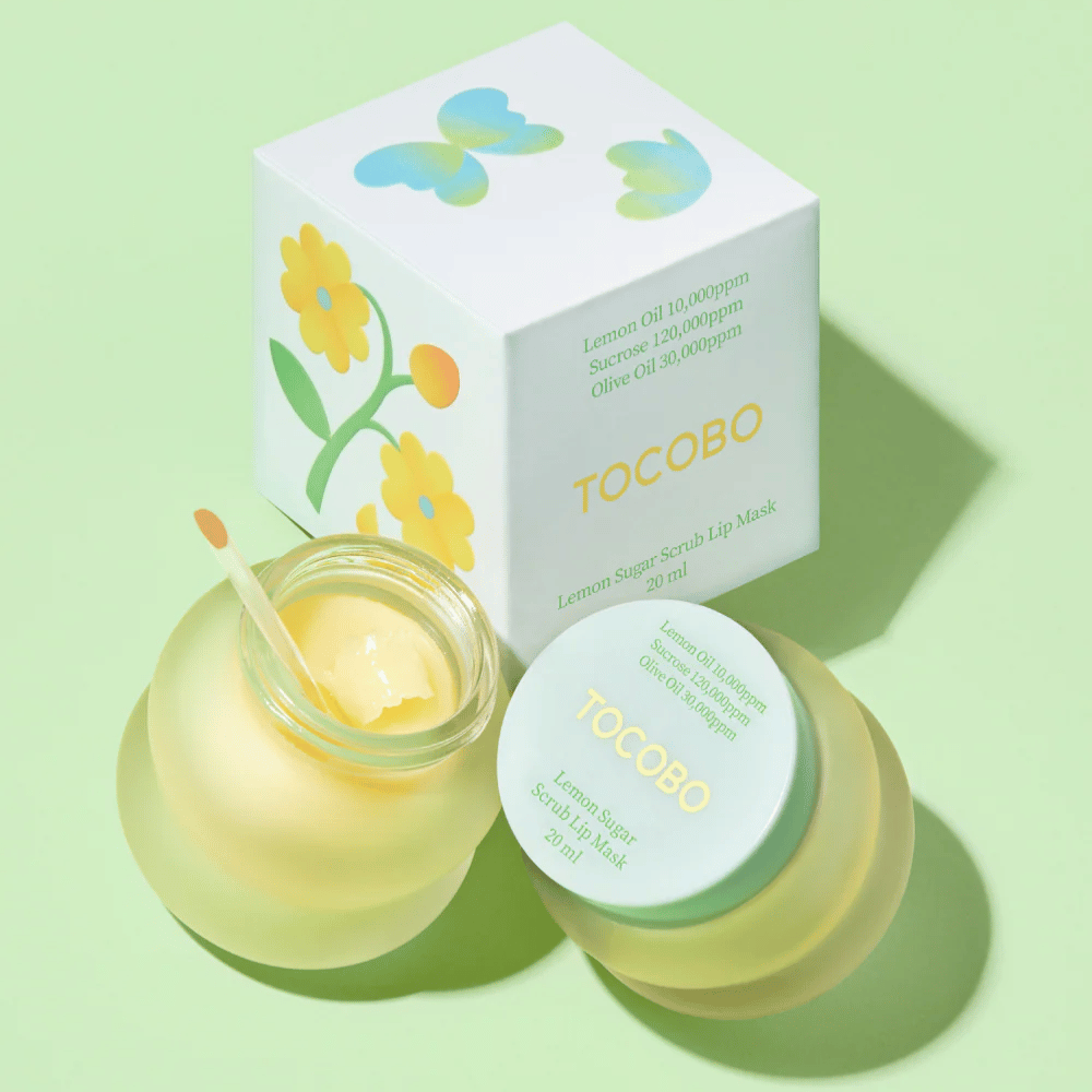 Tocobo Lemon Sugar Scrub Lip Mask sammen med sin emballasje med blomsterdesign på en lysegrønn bakgrunn.