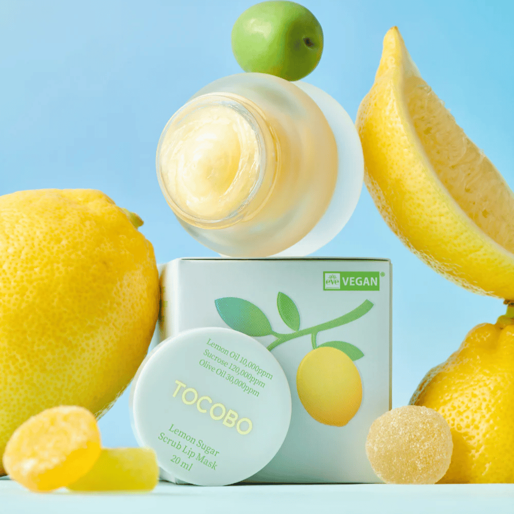 Krukke med Tocobo Lemon Sugar Scrub Lip Mask plassert blant sitroner og emballasje, merket som vegansk vennlig.