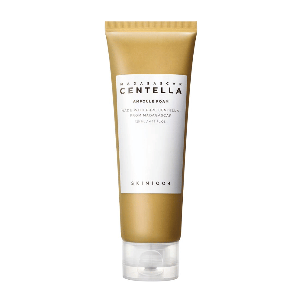 Bilde viser en tube av "Madagascar Centella Ampoule Foam" fra merket SKIN1004. Det er et renseprodukt for ansiktet som inneholder 125 ml / 4.22 fl.oz. Formelen er basert på ren Centella ekstrahert fra planter i Madagaskar. Produktet er designet for å skånsomt rense og pleie huden.