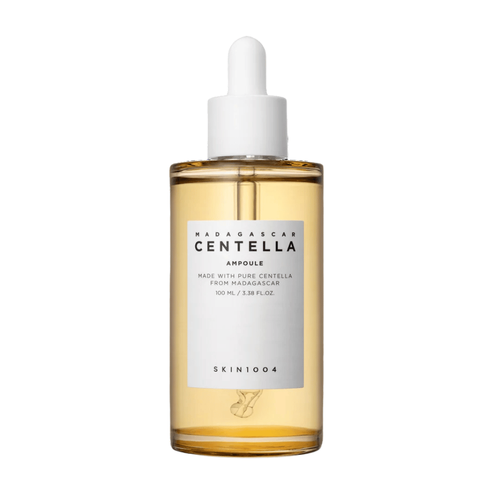 Bildet viser en flaske med "Madagascar Centella Asiatica 100 Ampoule" fra SKIN1004. Flasken inneholder 100 ml og påstår å være laget med ren Centella fra Madagaskar. Produktet ser ut til å være et hudpleieserum og den enkle etiketten gir et inntrykk av renhet og naturlighet. Flasken med dråpekork antyder at dette er et nøye dosert hudpleieprodukt.