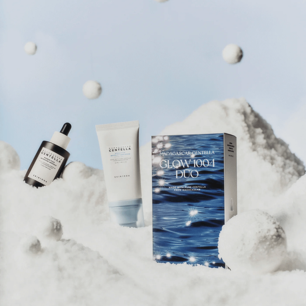 Bildet viser hudpleiesettet "Madagascar Centella Glow 1004 Duo" fra SKIN1004, plassert mot en bakgrunn som forestiller snø og himmel.