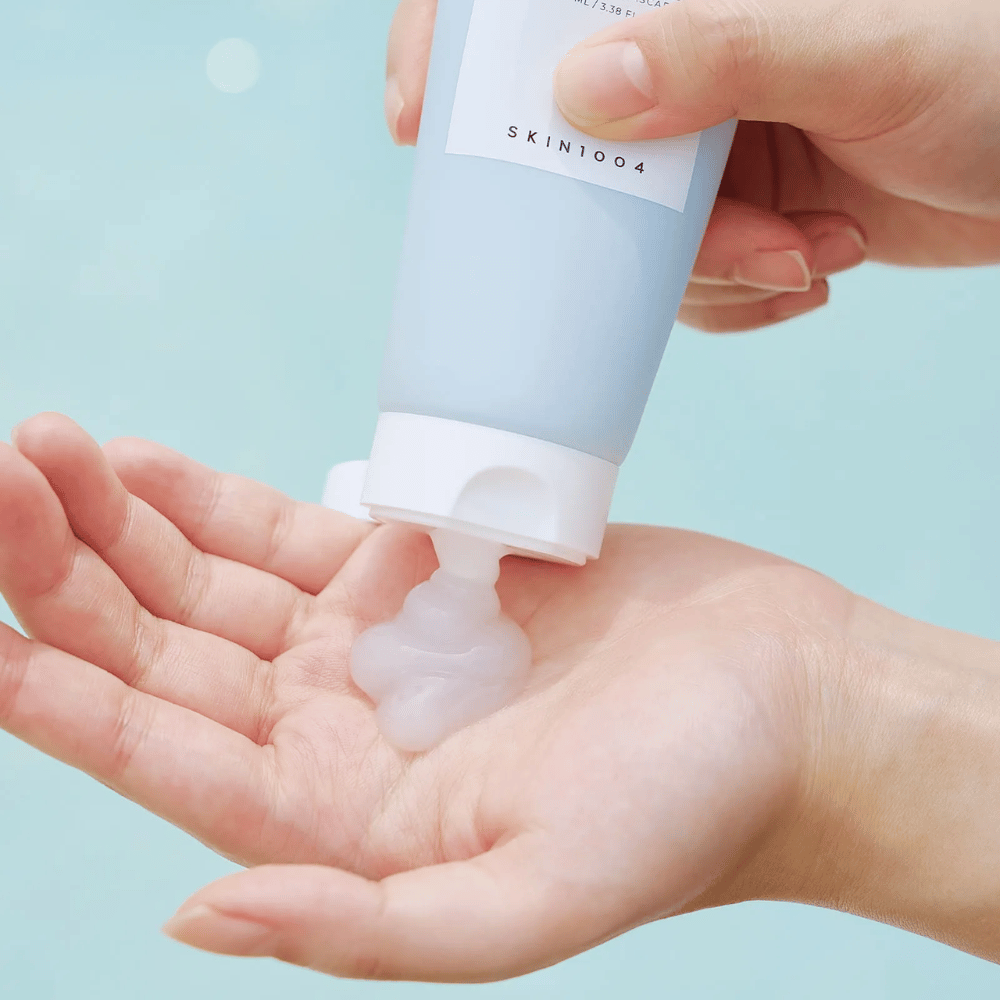 Bildet viser noen som presser ut en klar geléaktig substans fra en tube merket "SKIN1004 Madagascar Centella Hyalu-Cica Sleeping Pack" som inneholder 100 ml produkt.