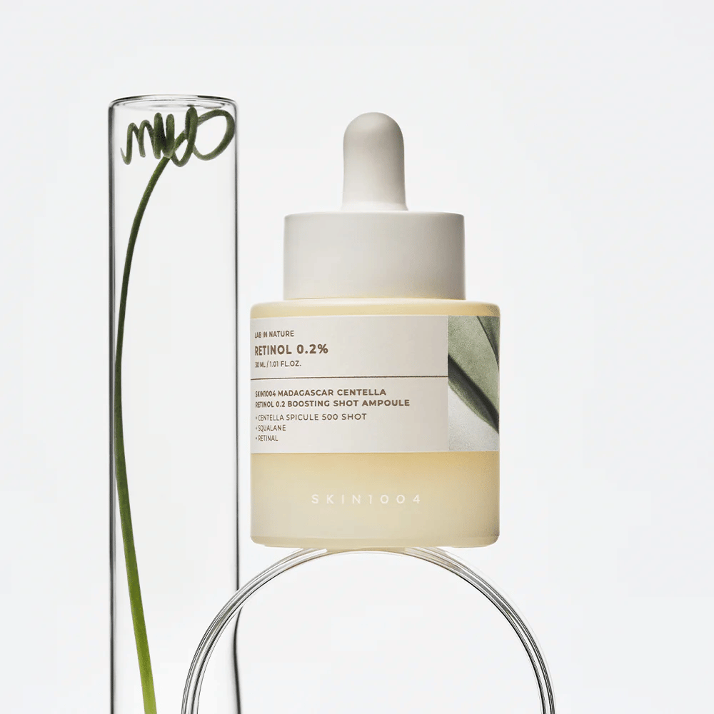 SKIN1004 Madagascar Centella Retinol 0.2 Boosting Shot Ampoule i livsstilsbilde med botaniske elementer – ansiktsserum som støtter hudens fornyelse og styrker hudbarrieren.