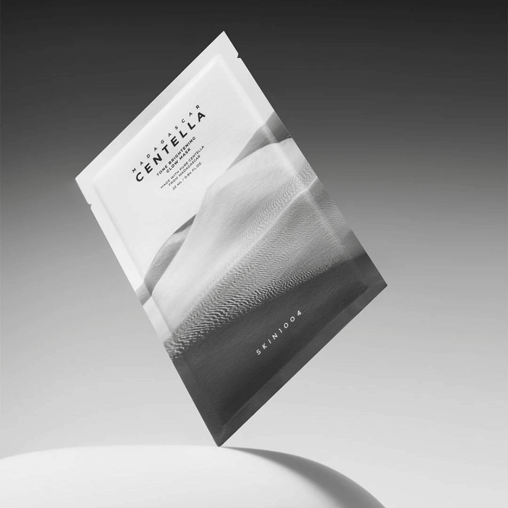 Sheet mask-pakning fra SKIN1004 svevende mot grå bakgrunn med minimalistisk design.