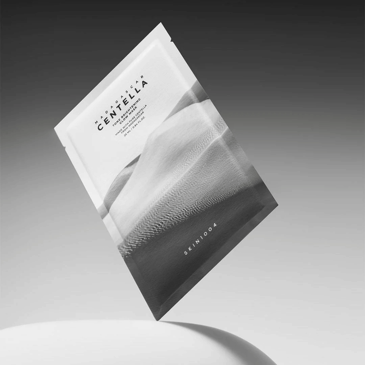 Sheet mask-pakning fra SKIN1004 svevende mot grå bakgrunn med minimalistisk design.