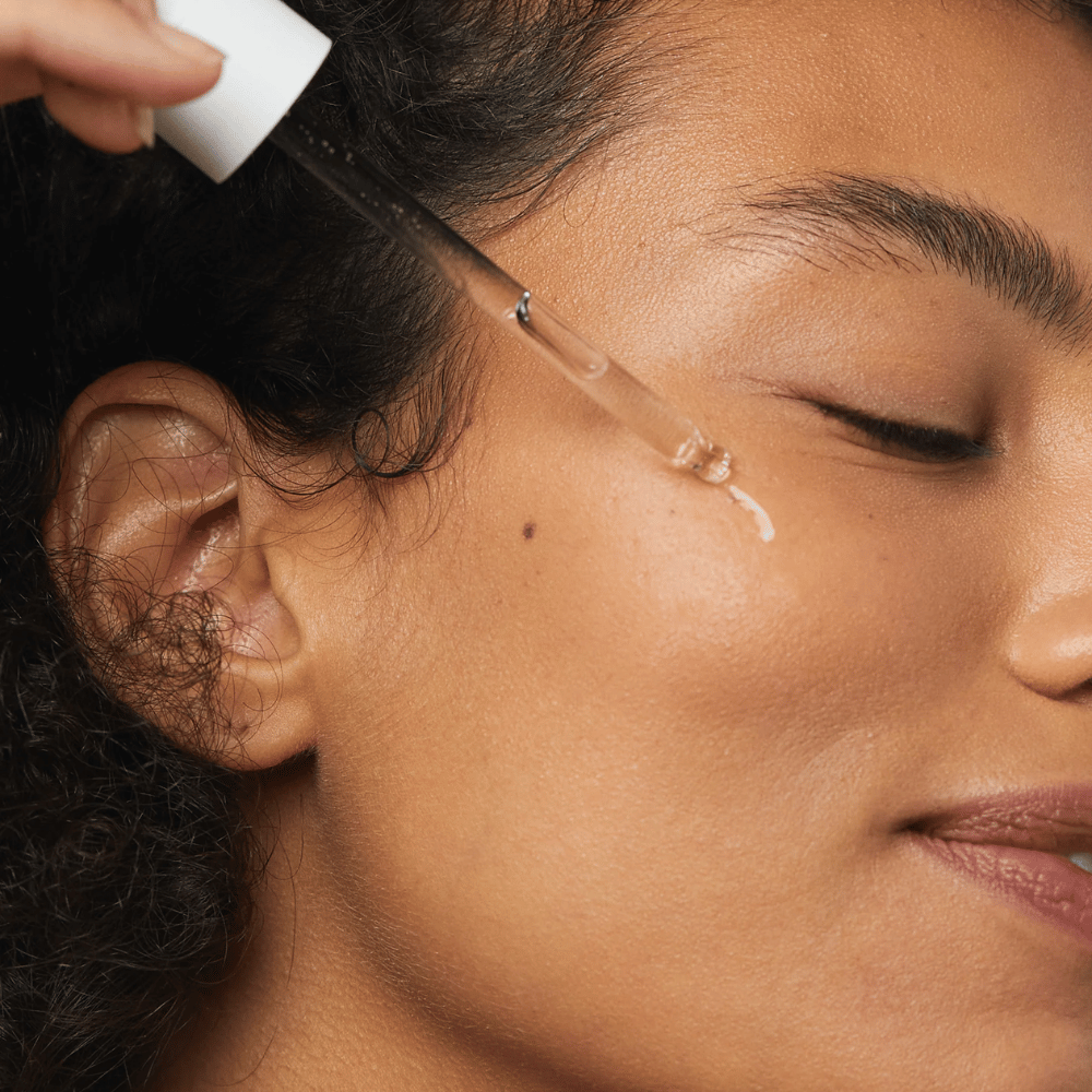 Kvinne påfører Skin1004 Madagascar Centella Hyalu-Cica First Ampoule på kinnet med en pipette.