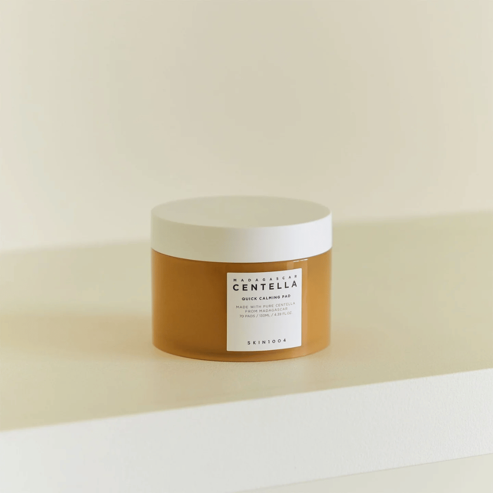 SKIN1004 Madagascar Centella Quick Calming Pad plassert på hvit hylle – ravfarget boks med hvitt lokk og tydelig etikett foran.