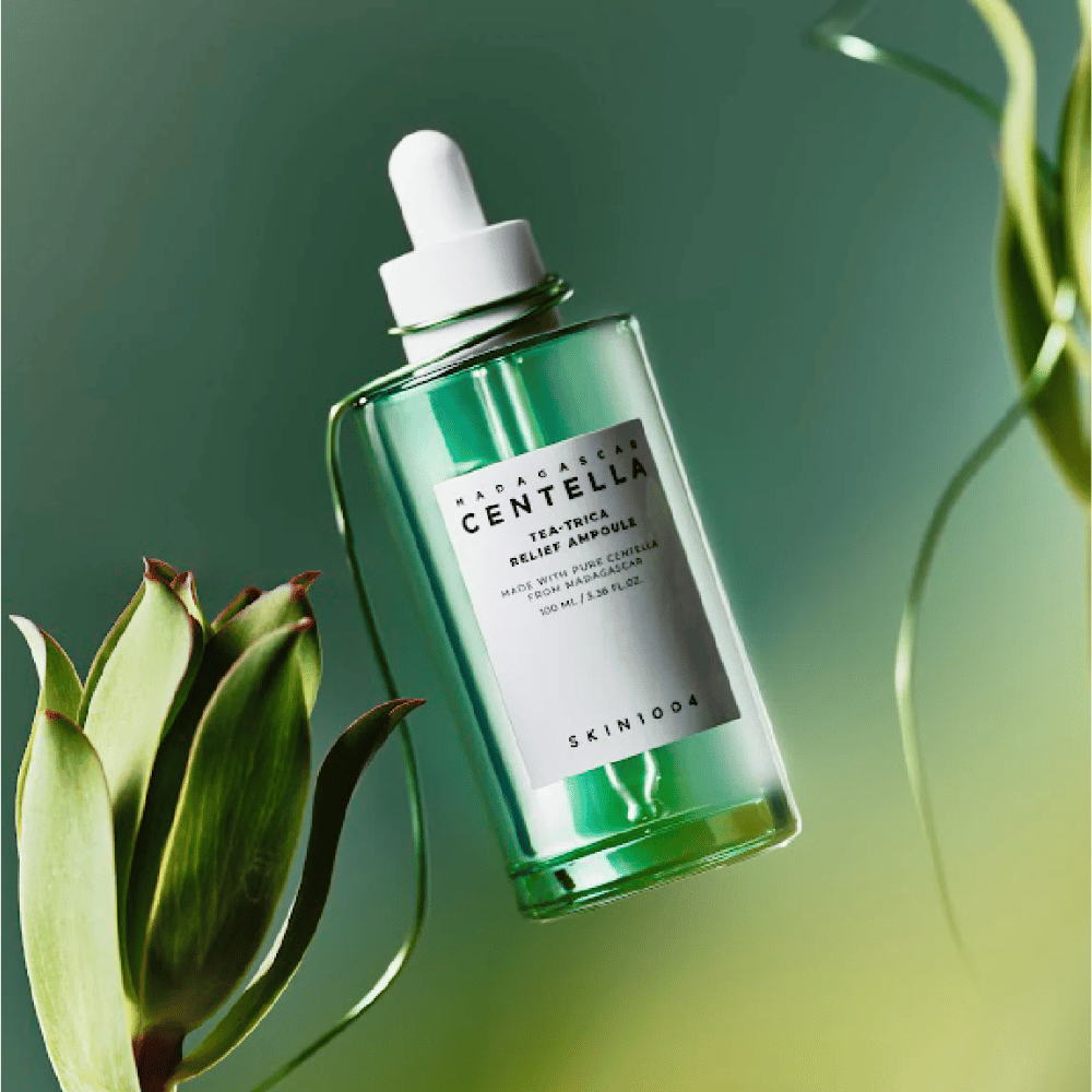 SKIN1004 Madagascar Centella Tea-Trica Relief Ampoule – grønn glassflaske med pipette, hvit etikett og 100 ml innhold, fotografert mot grønn bakgrunn med planteelementer.
