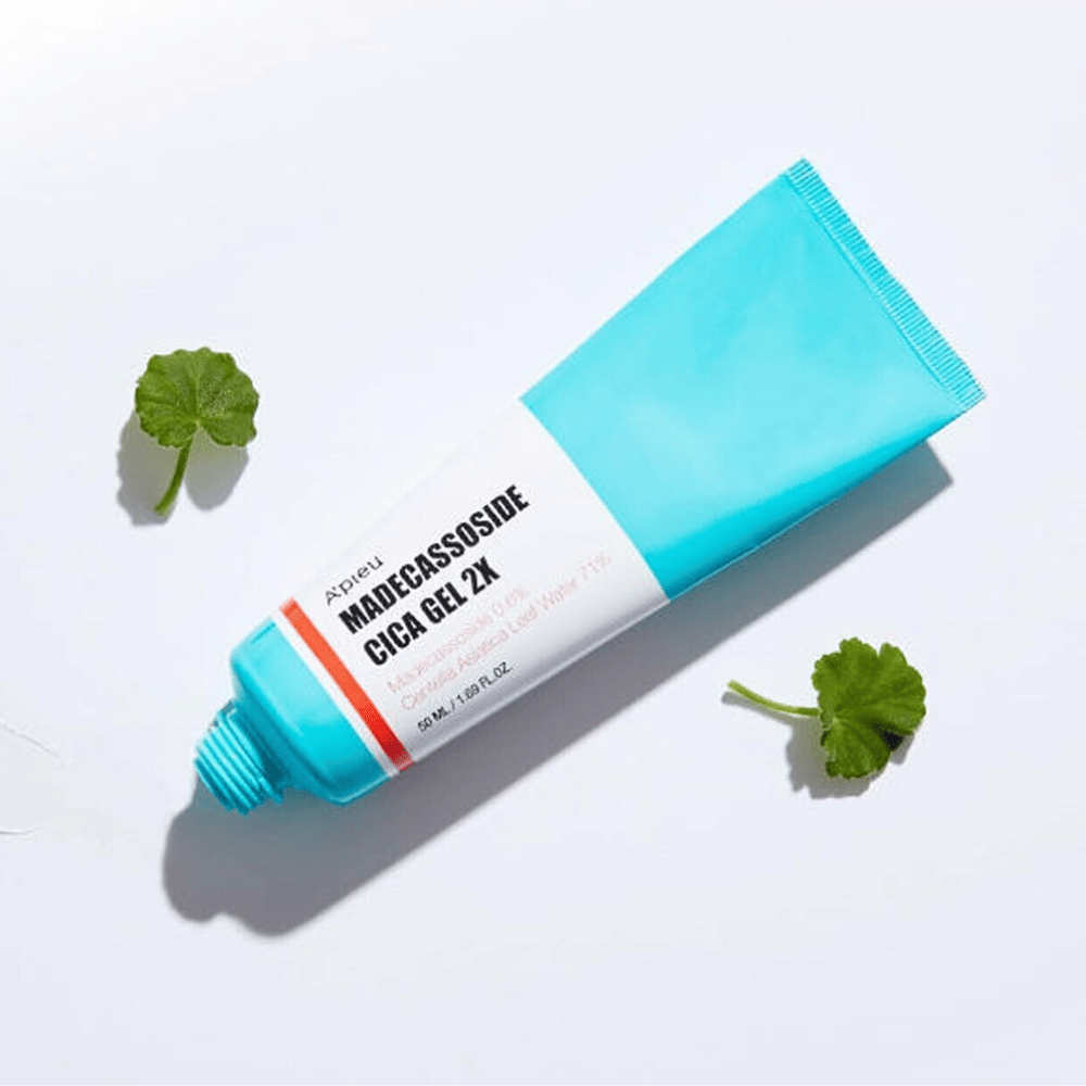 A’pieu Madecassoside Cica Gel 2X i blå tube med hvit etikett, omgitt av tre grønne centella asiatica-blad på hvit bakgrunn.