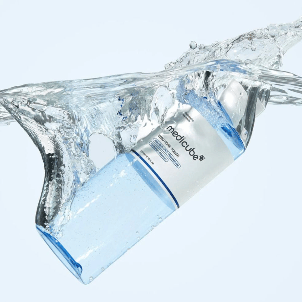 Medicube Zero Pore Toner 250 ml, eksfolierende toner med AHA, BHA og PHA. Gjennomsiktig blå flaske omgitt av et stort vannsprut.