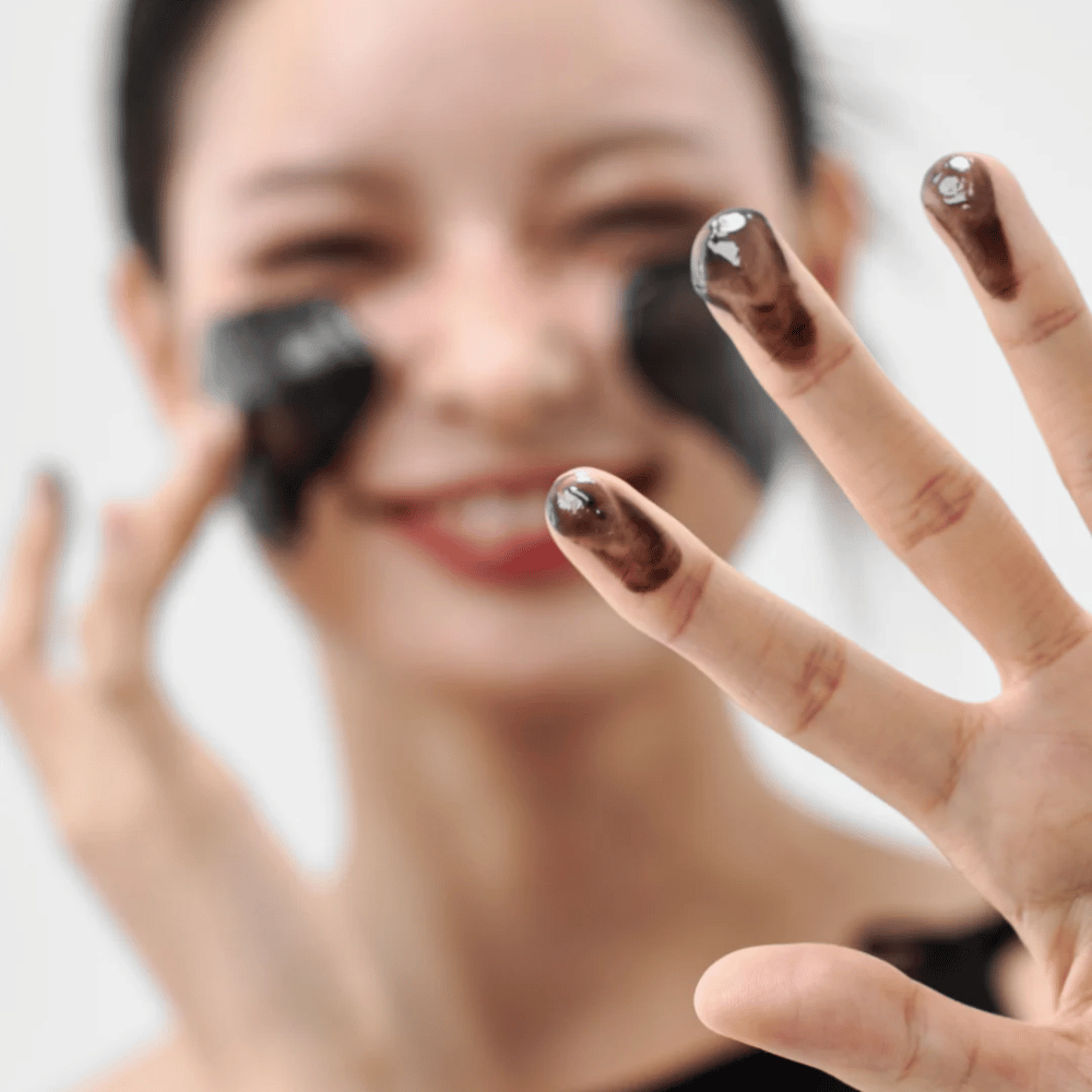 Modell påfører Hvordan Midnight Soothing Cleansing Balm på huden. Kremet rensebalm som renser i dybden og etterlater huden myk og balansert.