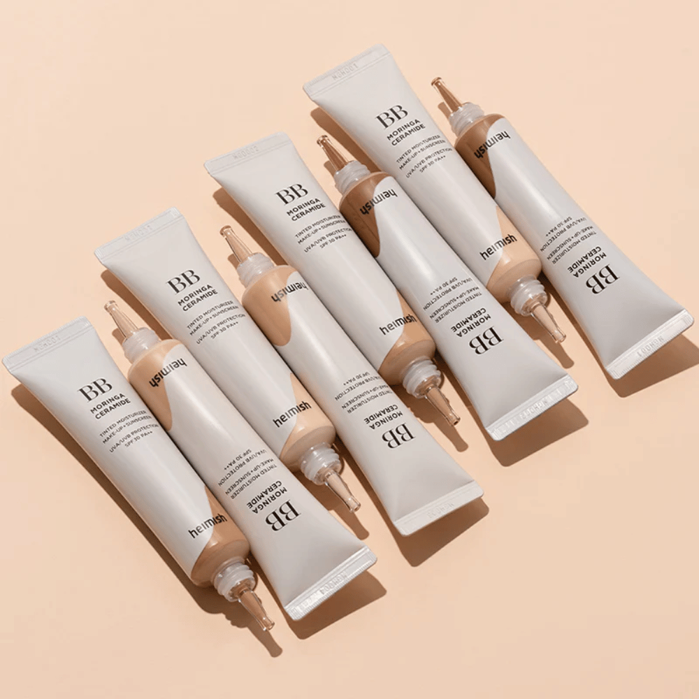Flere tuber av Heimish Moringa Ceramide BB Cream arrangert på lys beige bakgrunn. Bildet fremhever de ulike nyansene og produktets elegante, minimalistiske emballasjedesign.
