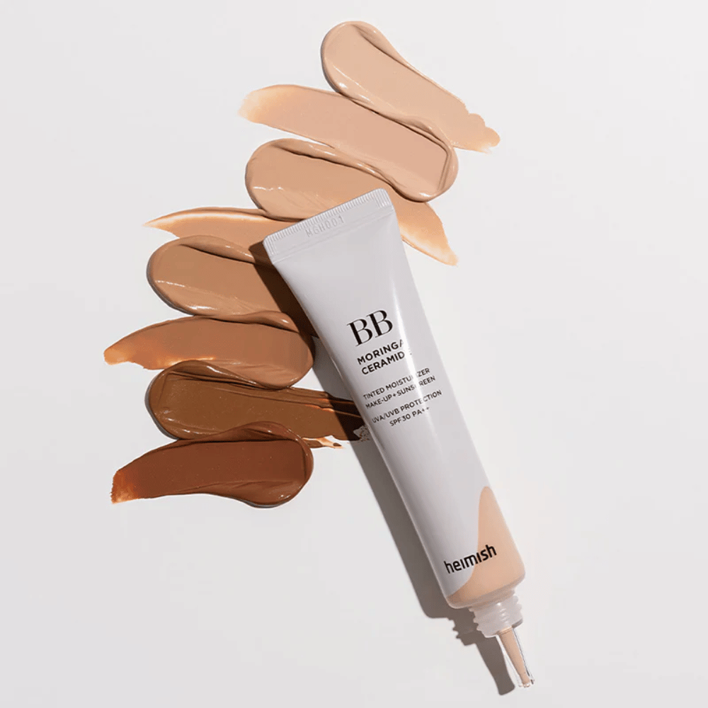 Heimish Moringa Ceramide BB Cream omgitt av flere nyanseprøver i ulike hudtoner. Bildet viser produktets brede fargeutvalg og den kremete konsistensen som gir naturlig dekning og jevn hudtone.