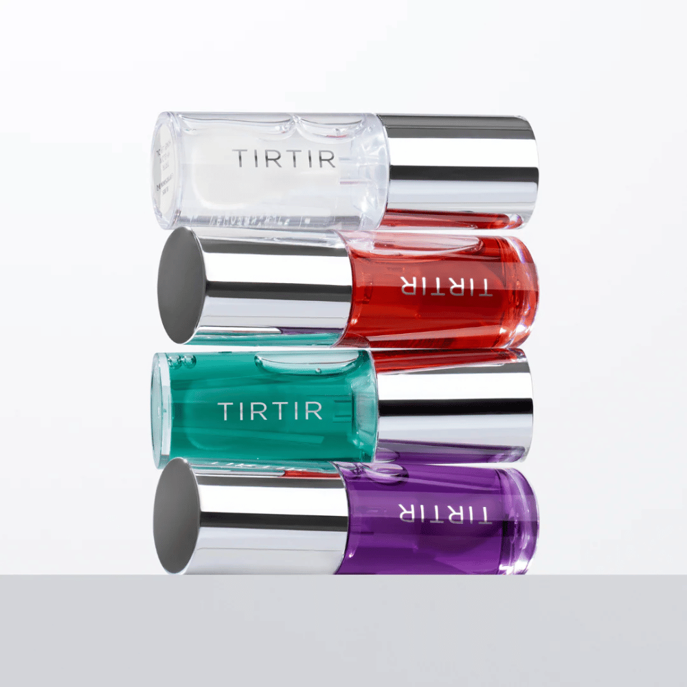Fire TIRTIR My Glow Lip Oil i forskjellige farger – gjennomsiktig, rød, grønn og lilla – stablet på hverandre med sølvfargede lokk mot hvit bakgrunn.