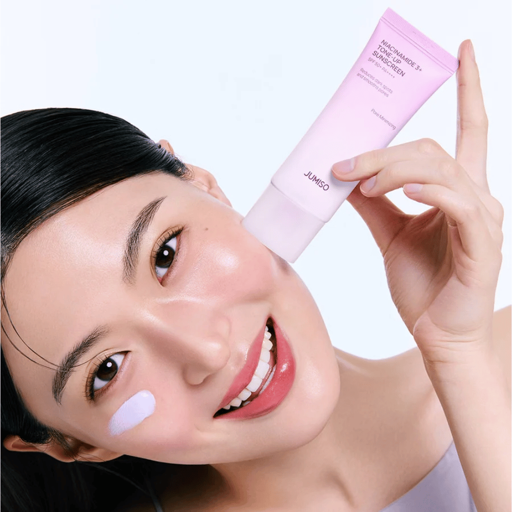 Modell påfører JUMISO Niacinamide 3+ Tone-Up Sunscreen SPF50+ PA++++ for UV-beskyttelse, jevnere hudtone og naturlig glød.