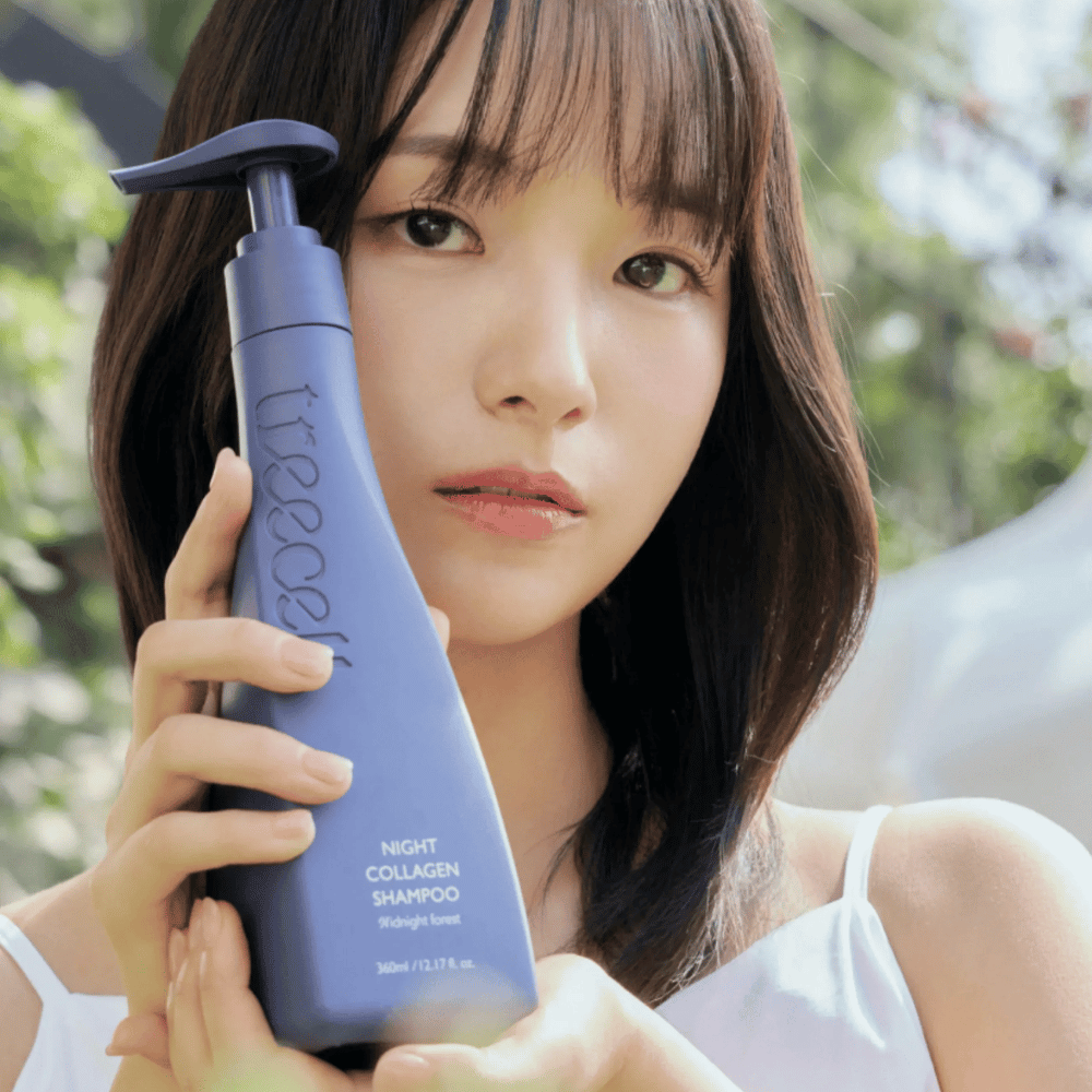 Kvinne holder opp Treecell Night Collagen Shampoo Midnight Forest i et naturlig miljø. Bildet formidler friskt hår, glans og premiumfølelse med fokus på hår- og hodebunnspleie.