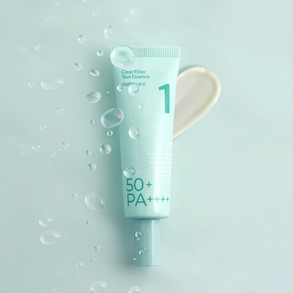 En lyseblå tube med No.1 Clear Filter Sun Essence SPF 50+ PA++++. Tuben er dekorert med vanndråper og en klatt av produktet vises ved siden av. Produktet er designet for å gi høy solfaktor og beskyttelse mot UVA/UVB-stråler.