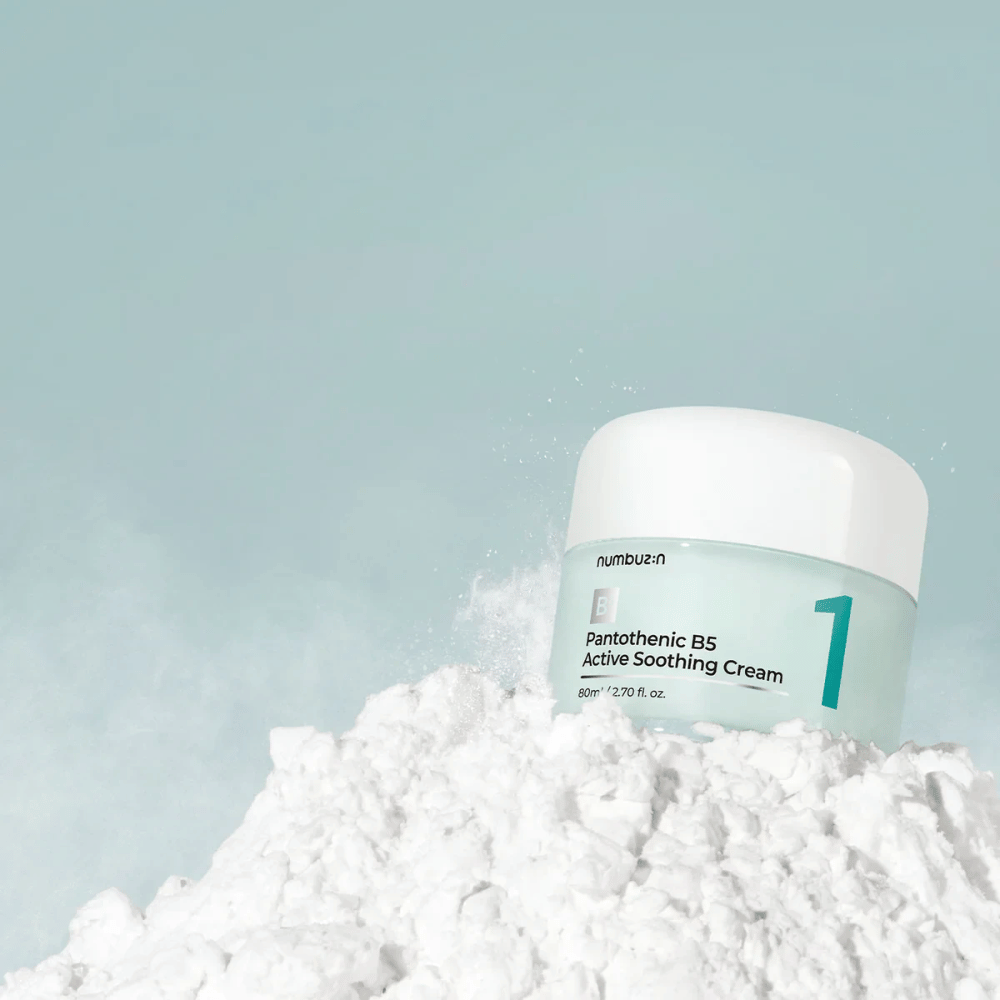 Numbuzin No.1 Pantothenic B5 Active Soothing Cream 80 ml i lysegrønn boks med hvitt lokk, plassert på en haug av hvitt pulver mot lys bakgrunn.