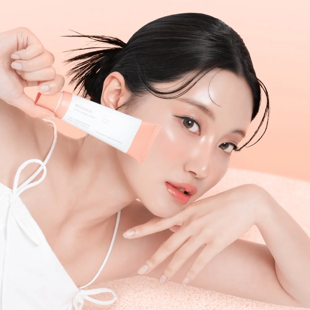 Person med strålende hud holder Mixsoon PDRN Collagen Cream nær kinnet. Kremen fukter, styrker elastisiteten og gir en frisk glød.