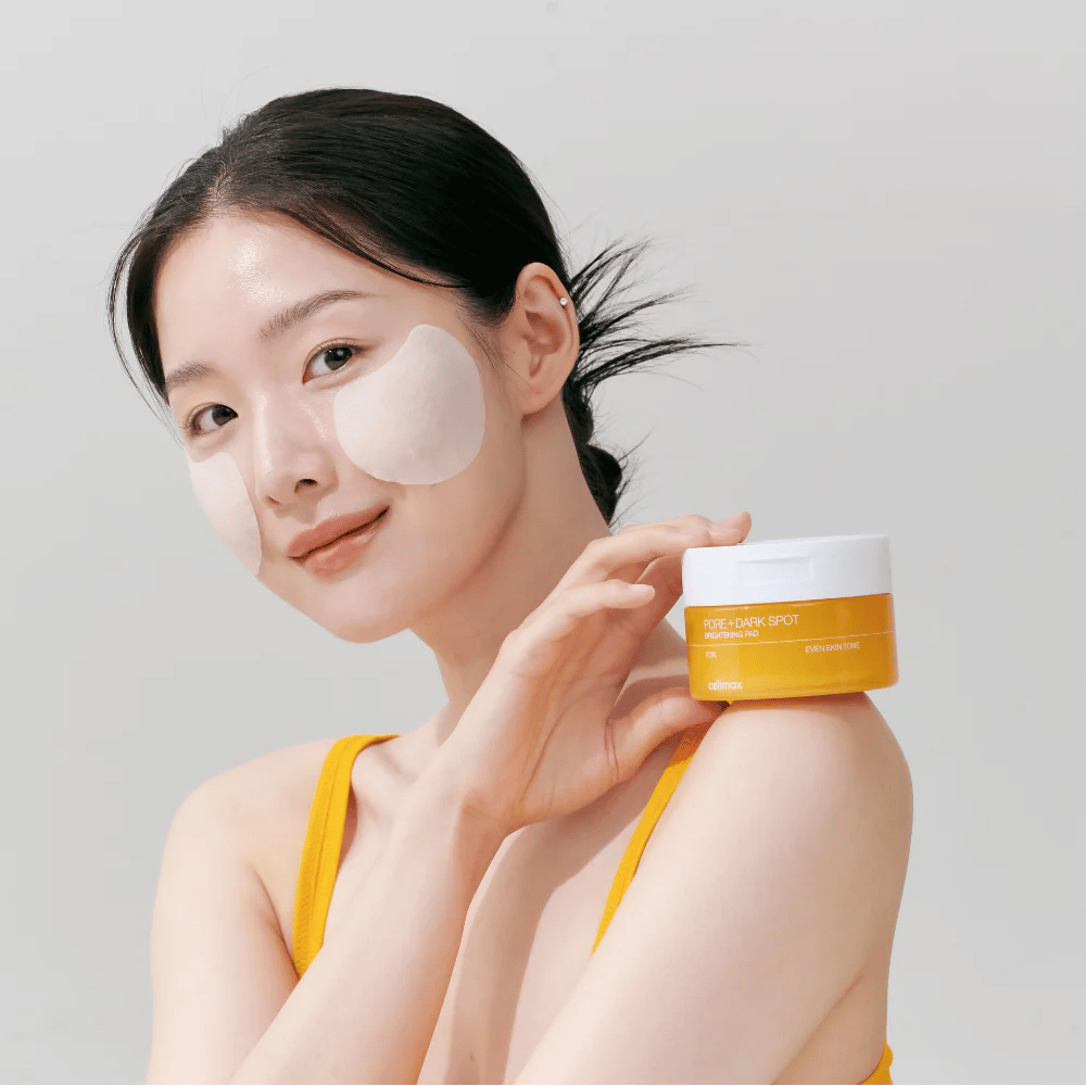Kvinne påfører Celimax Pore + Dark Spot Brightening Pad – koreanske pads som jevner ut hudtonen og reduserer porer og pigmentflekker.