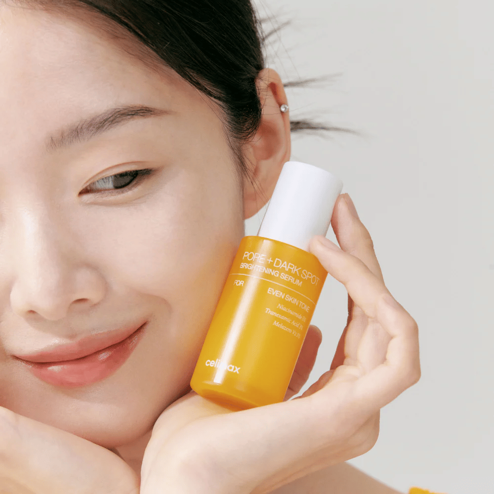 Modell holder Celimax Pore + Dark Spot Brightening Serum nær ansiktet, viser strålende hud.