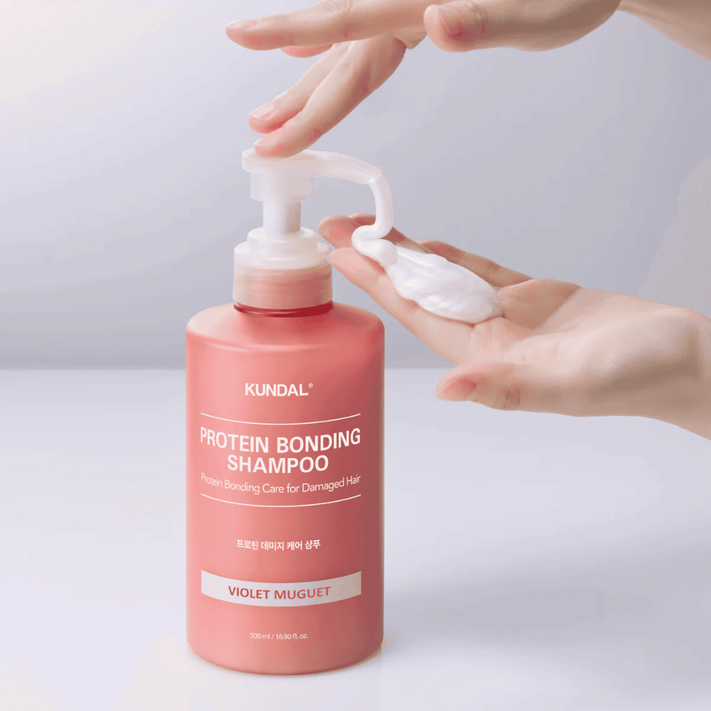 Hånd pumper ut KUNDAL Protein Bonding Shampoo Violet Muguet i kremet konsistens, reparerende sjampo for skadet hår.