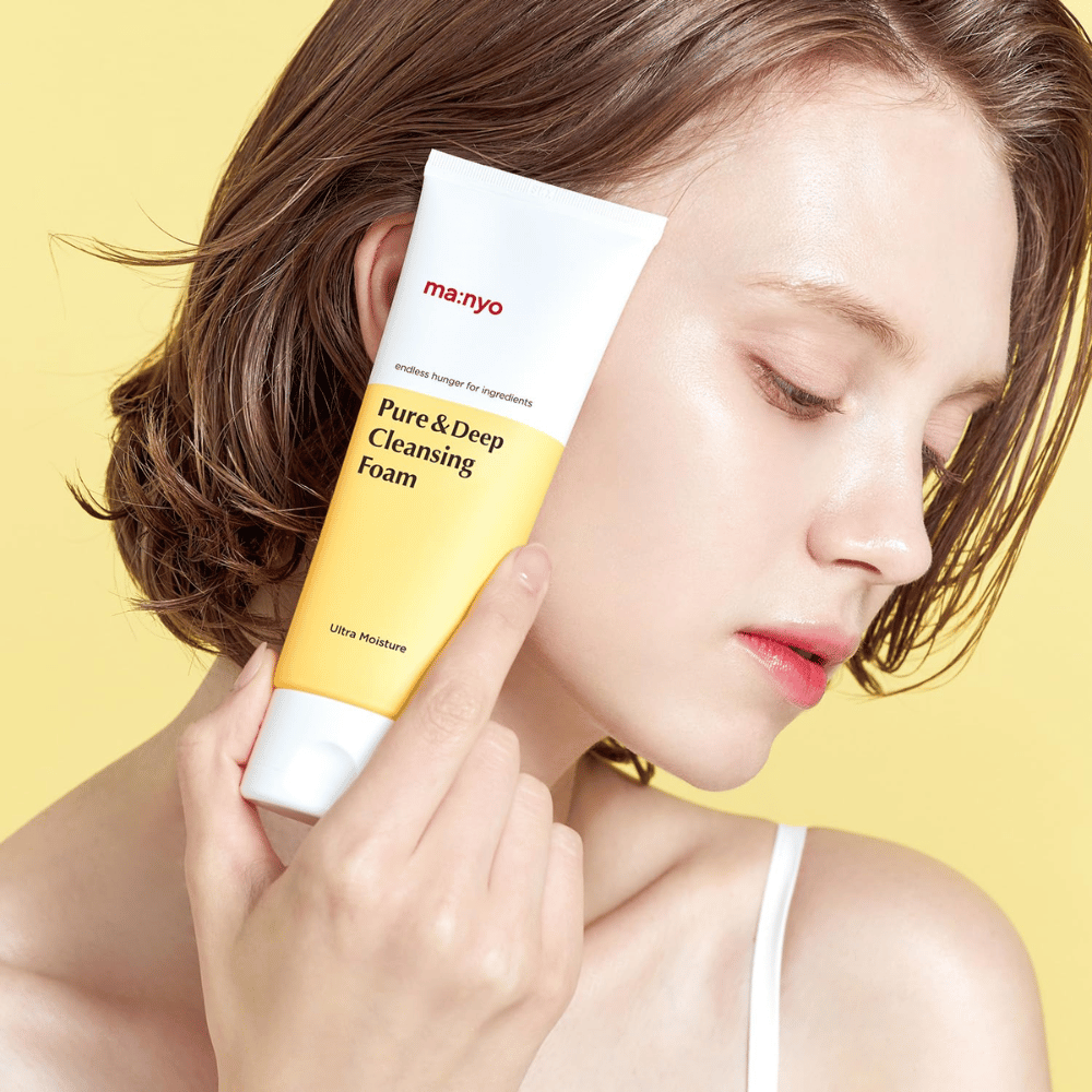 Kvinne med frisk, fuktet hud holder Ma:nyo Pure & Deep Cleansing Foam – mild ansiktsrens som gir glød og balanse med naturlige ingredienser.