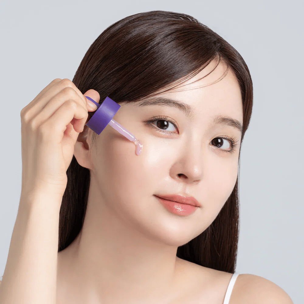Påføring av Cellology Purple Carrot Pore Ampoule med pipette på ansiktet for porepleie og jevnere hudtekstur.