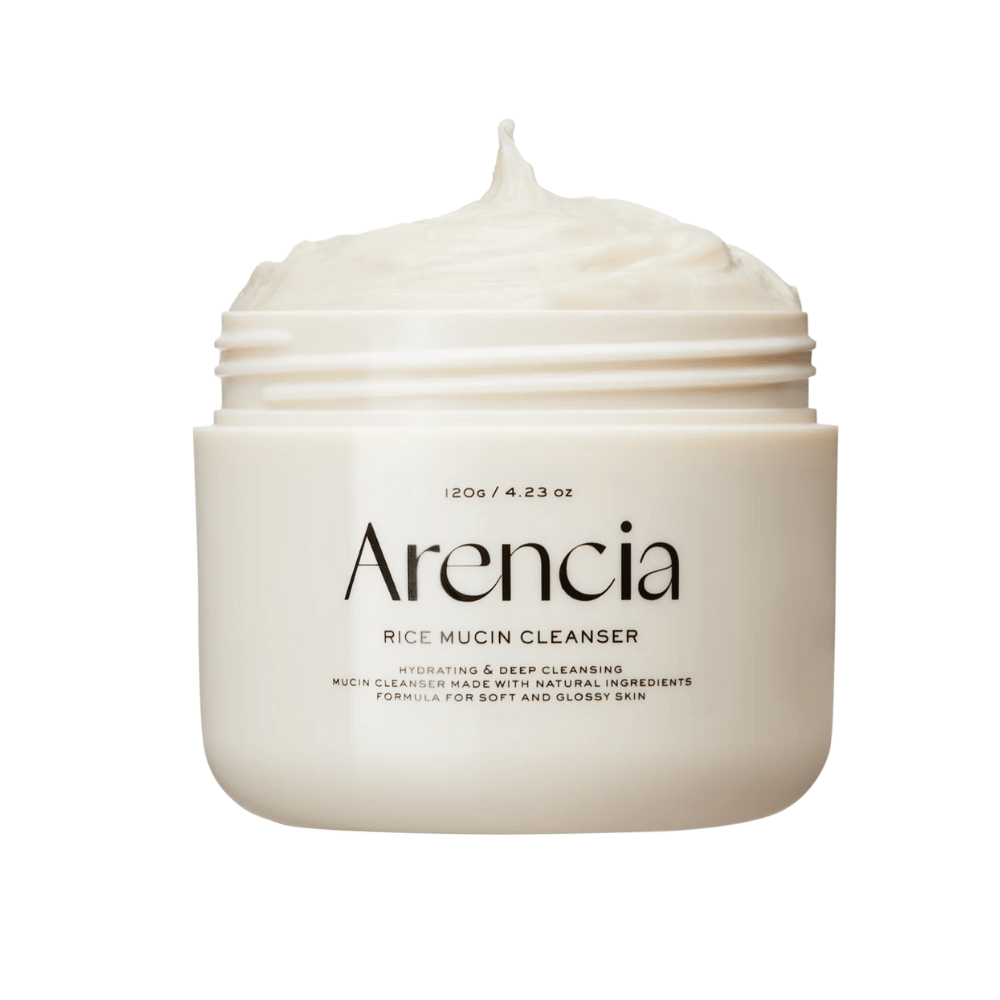 Produktbilde på Arencia Rice Mucin Cleanser i en hvit krukke med kremet, pisket tekstur som stikker opp fra åpningen. Tekst på emballasjen fremhever fuktighet og dyprengjøring.