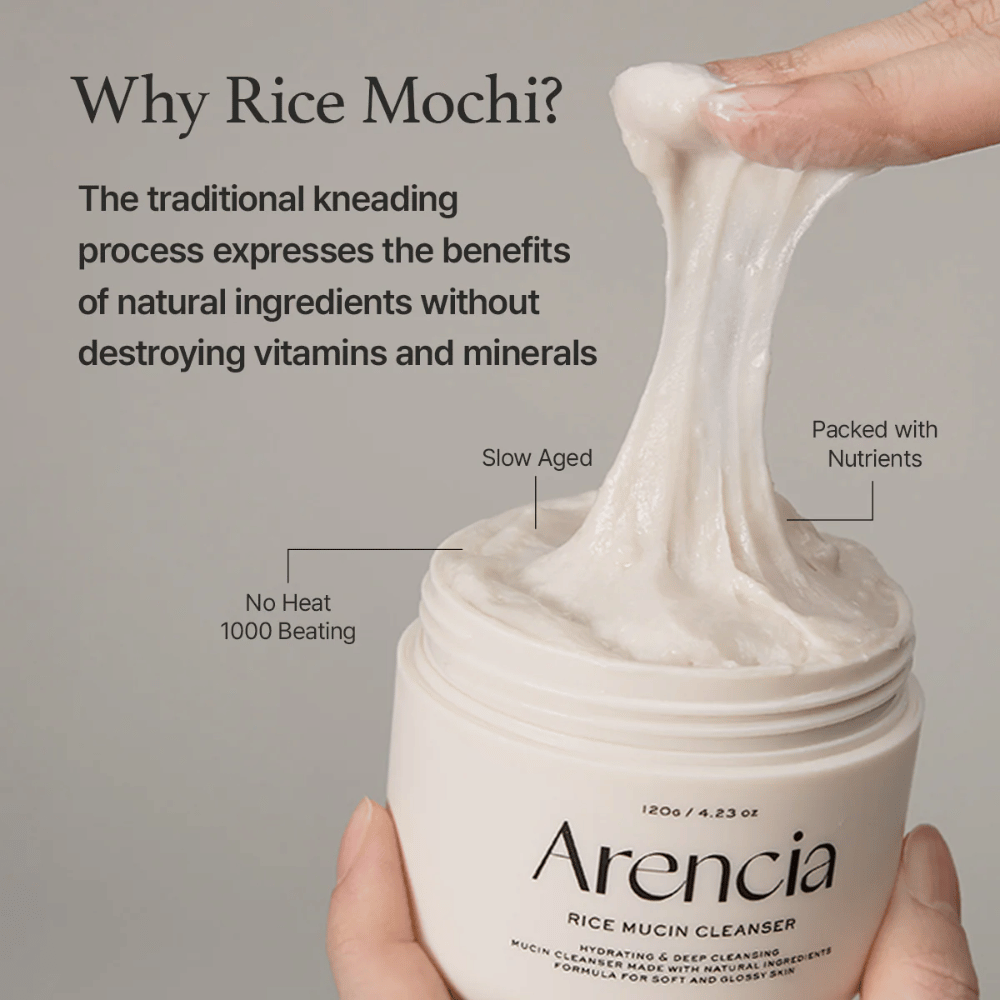 Hånd som løfter opp en elastisk, hvit rengjøringskrem fra en krukke merket "Arencia Rice Mucin Cleanser". Teksten beskriver tradisjonell knaing som bevarer næringsstoffer uten å ødelegge vitaminer og mineraler.