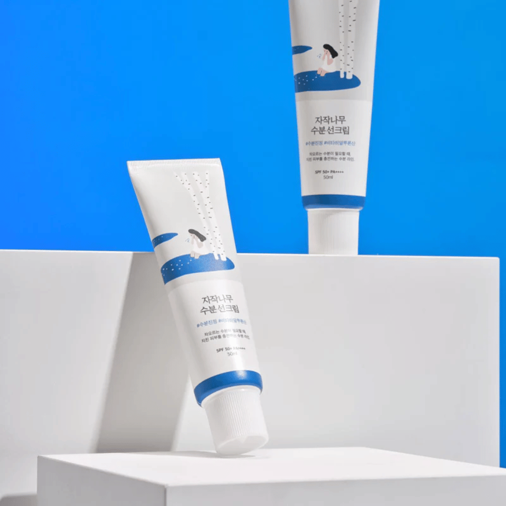 To tuber med Round Lab Birch Juice Moisturizing Sunscreen SPF50+ PA++++ 50ml som sitter oppå en blå bakgrunn.