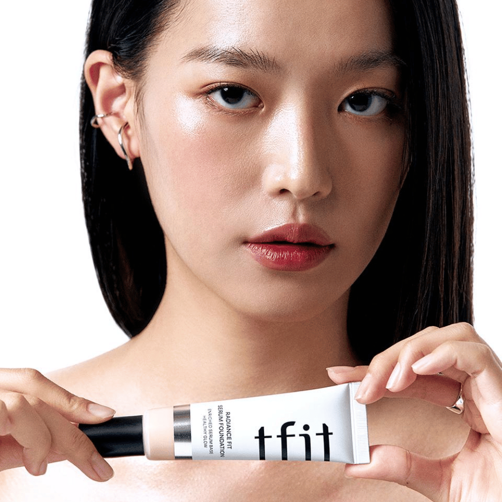 Modell med glansfull, jevn hud holder i TFIT Radiance Fit Serum Foundation, som fremhever produktets naturlige finish og glød.