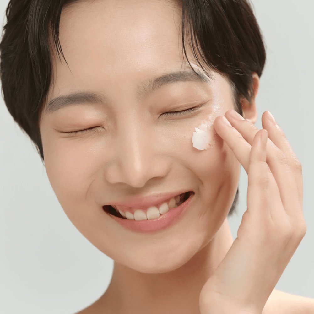 Modell med glødende hud påfører Beauty of Joseon Radiance Cleansing Balm – koreansk rensebalm som smelter bort sminke og urenheter.
