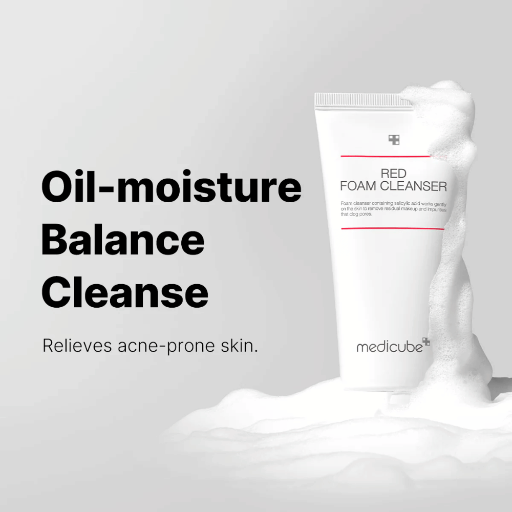 Tube med Medicube Red Foam Cleanser står oppreist blant skummende skum. Teksten "Oil-moisture Balance Cleanse" vises til venstre, med beskrivelsen "Relieves acne-prone skin" under. Bakgrunnen er lysegrå.