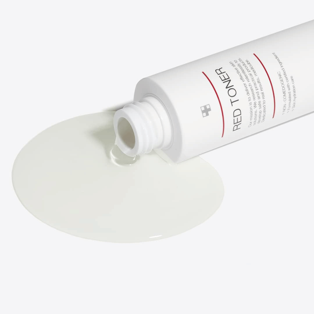 Åpen flaske med medicube Red Toner som helles ut på en hvit overflate – viser produktets lette og flytende konsistens.
