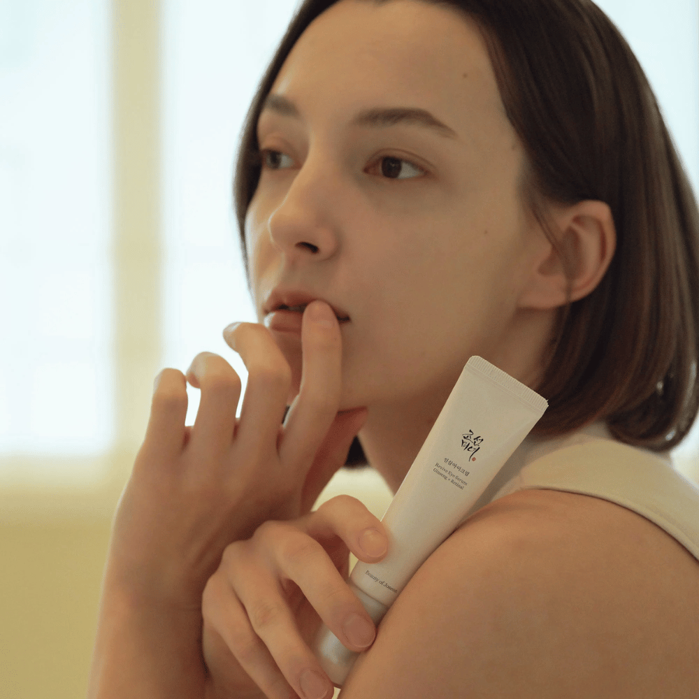 Modell holder i Beauty of Joseon Revive Eye Serum og påfører forsiktig på huden for en fuktet og glatt øyekontur.