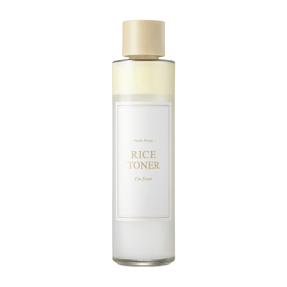 En transparent flaske med gullokk og etikett som angir "Rice Toner I'm from Yeojü, Korea". Flasken inneholder en lys væske, trolig toner basert på risekstrakt. Designen er ren og minimalistisk. Bakgrunnen er hvit.
