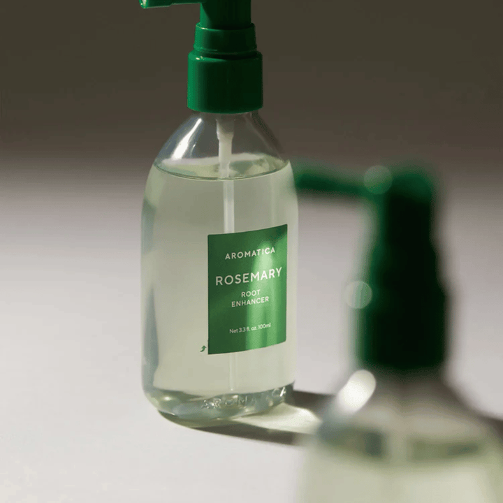 Nærbilde av AROMATICA Rosemary Root Enhancer med grønn applikatorspiss. Bildet fokuserer på flaskens design og den presise påføringen direkte mot hodebunnen.