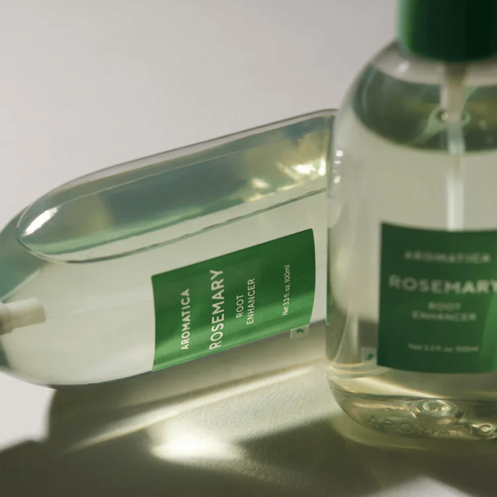 To AROMATICA Rosemary Root Enhancer-flasker med transparent beskyttelseshette og grønn etikett. Nærbilde som fremhever produktets premiumdesign og naturlige hårpleiekonsept.