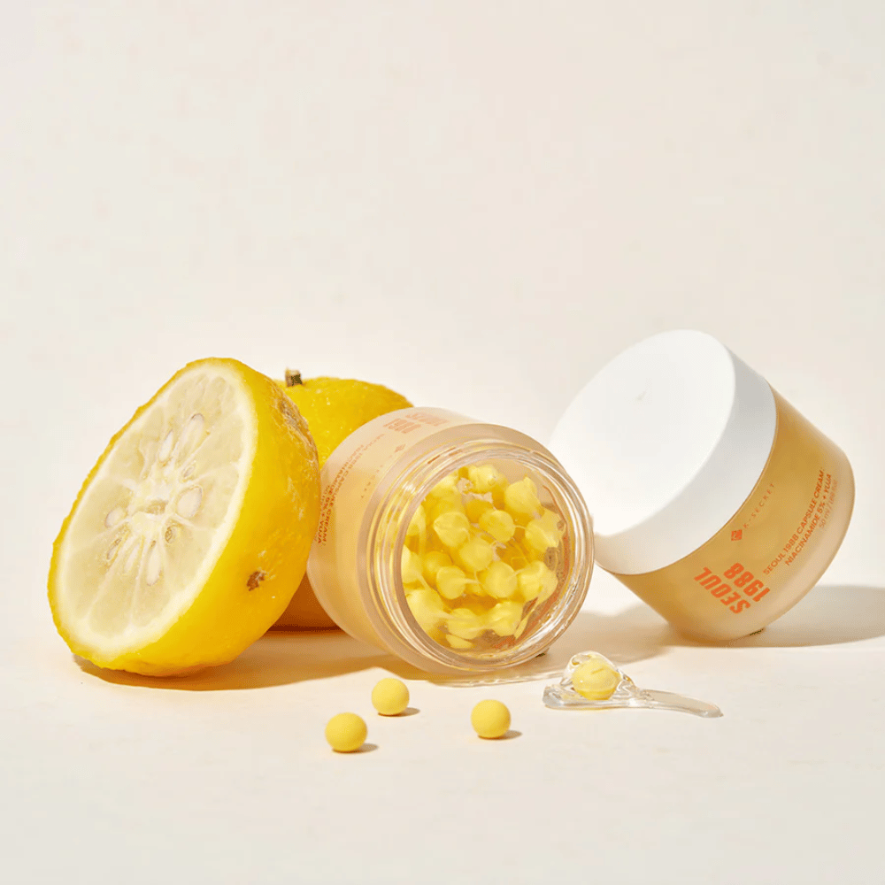 Åpen boks med gule kapsler ved siden av halvert yuja-frukt som fremhever C-vitaminrik formel.
