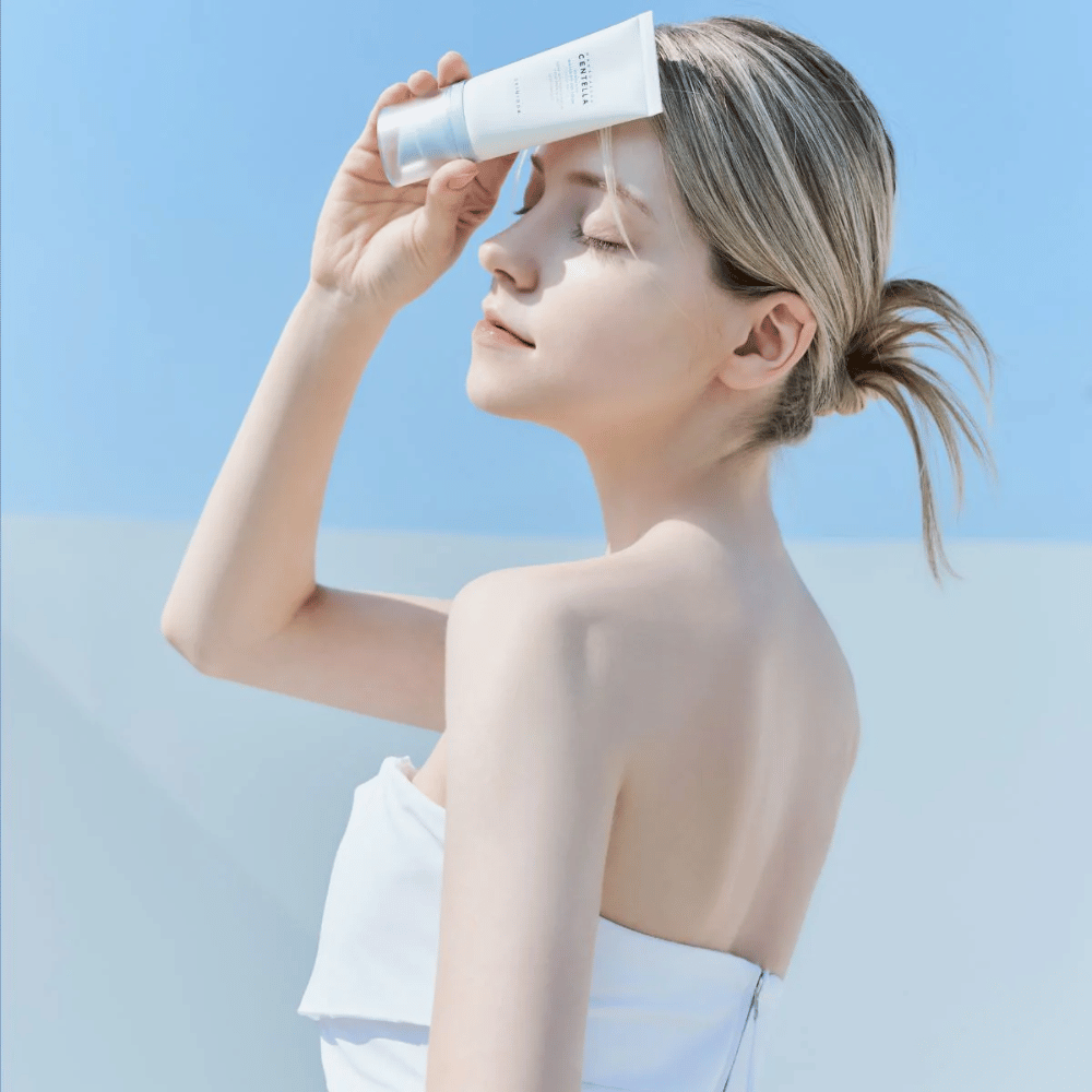 En kvinne påfører SKIN1004 Madagascar Centella Hyalu-Cica Water-Fit Sun Serum 50ml for å beskytte ansiktet fra UV-stråler.