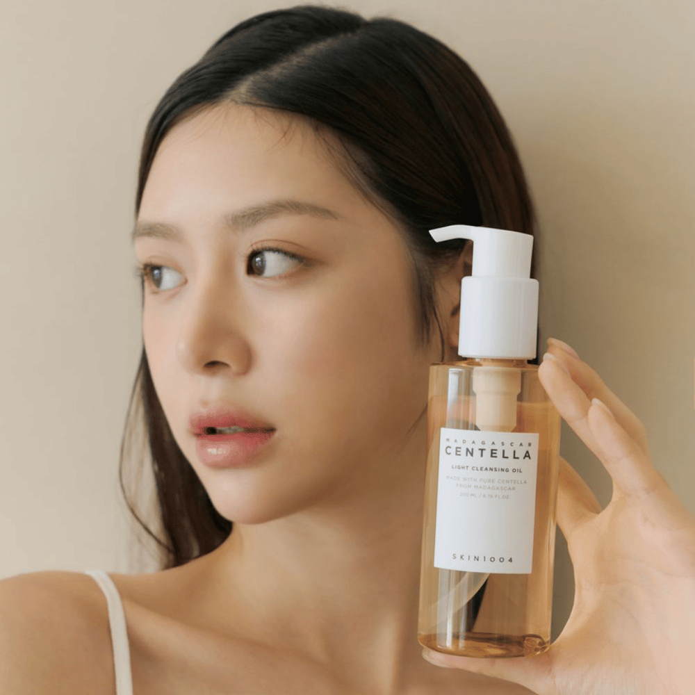En kvinne som holder opp en flaske SKIN1004 Madagascar Centella Light Cleansing Oil 200 ml ansiktsrens.